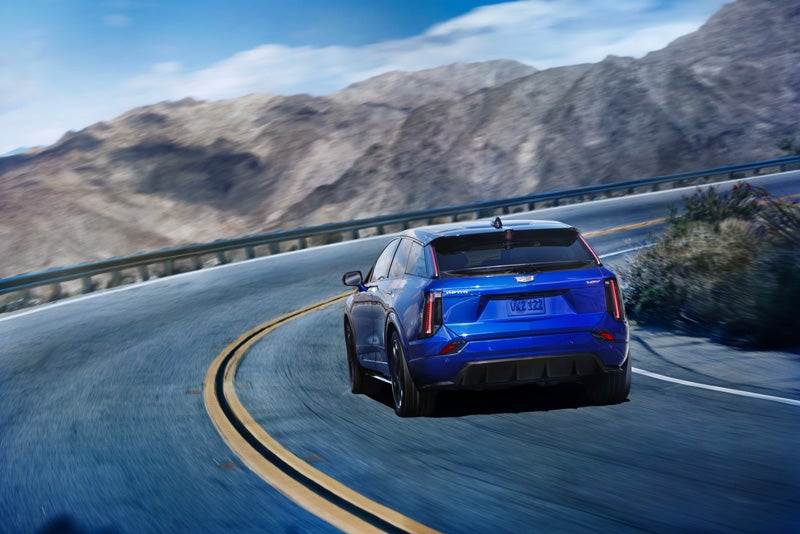 Rear View of a Blue 2026 OPTIQ-V Driving on a Curve of a Mountain Row | Wackerli Cadillac of Idaho Falls in Idaho falls ID